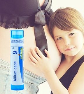 une petite fille qui se tient contre le ventre enceinte de sa mère avec un tube d'homéopathie