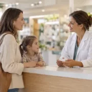 Un parent accompagné de son enfant échange avec une pharmacienne au comptoir.