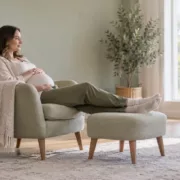 Une femme enceinte repose ses jambes sur un repose-pieds dans son salon.