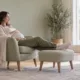 Une femme enceinte repose ses jambes sur un repose-pieds dans son salon.