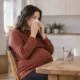 Une femme enceinte assise utilise un mouchoir, un verre d’eau posé près d’elle.