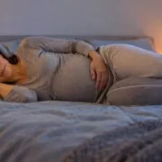 Une femme enceinte est allongée sur le côté avec un coussin de grossesse.